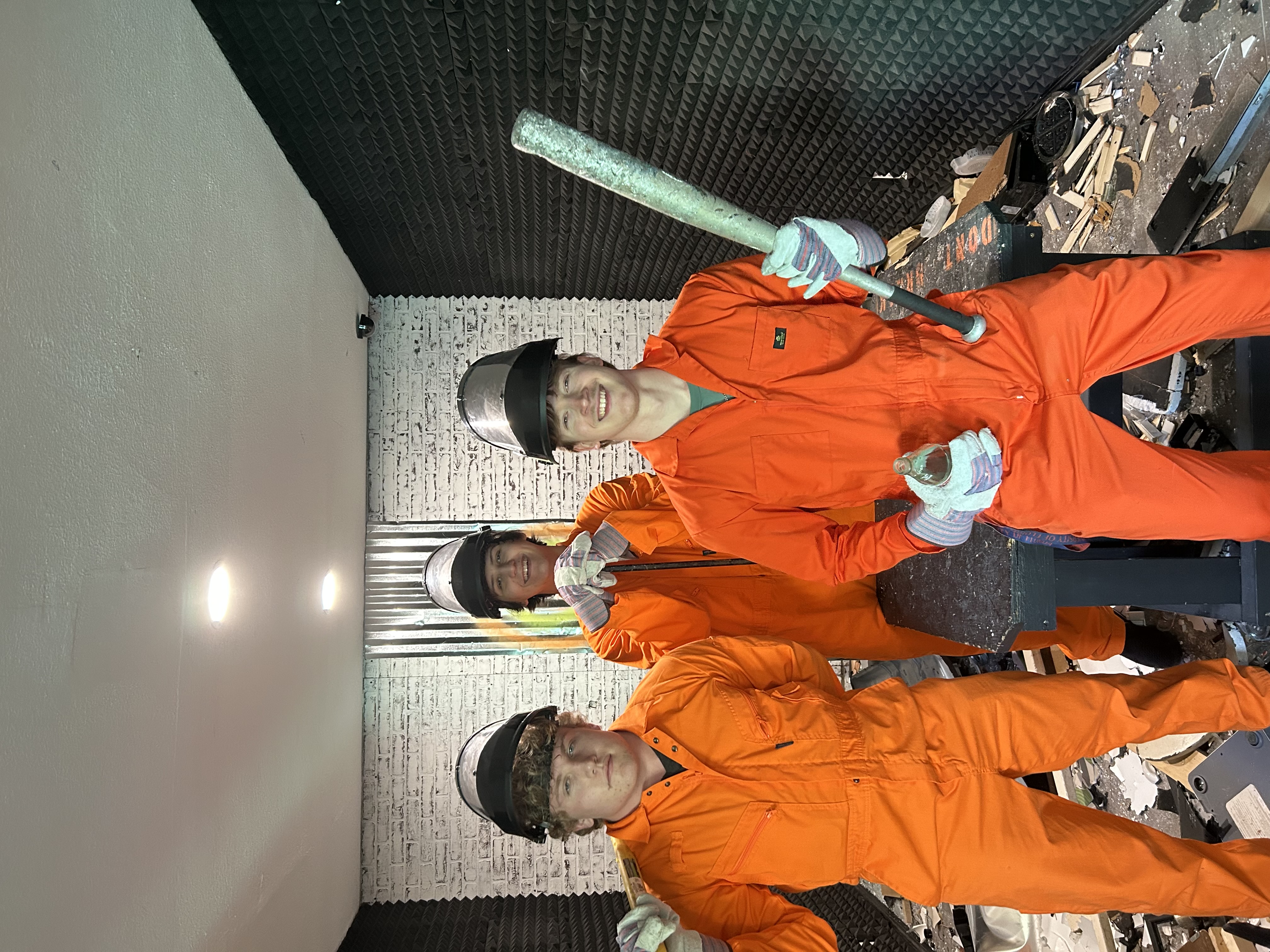 Three Crash Out customers celebrating inside the smash room surrounded by debris after a session